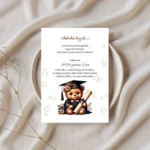 Ovis ballagási dekoráció: diplomás macis meghívó egy elegánsan terített asztalon, fehér tányérra helyezve, száraz virággal díszitve.