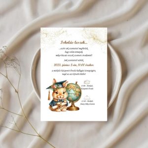 Elegáns ovis ballagási dekoráció: nyuszis meghívó földgömbbel, egy elegánsan terített asztalon, fehér tányérra helyezve.