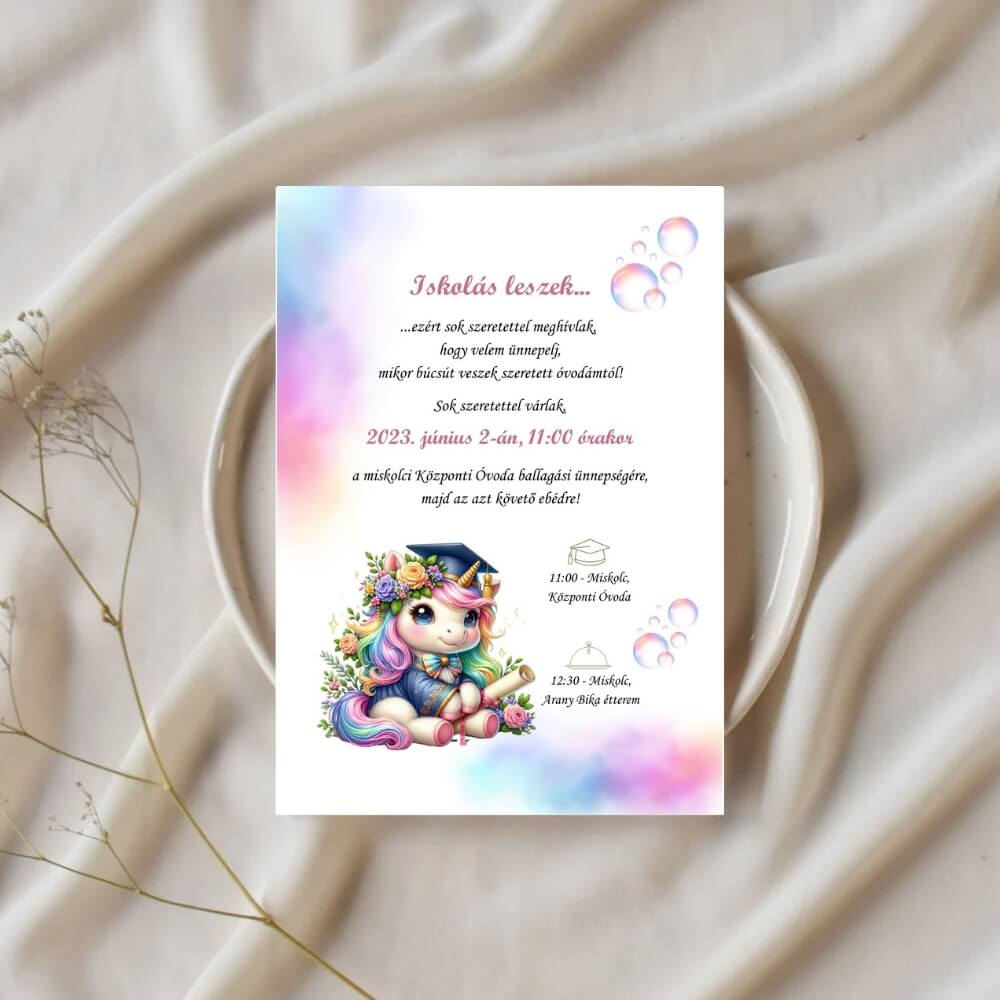 Unikornisos ballagási meghívó2 Varázslatos ovis ballagási meghívó unikornisos mintával, ünnepi asztali környezetben, elegáns fehér tányérra helyezve.