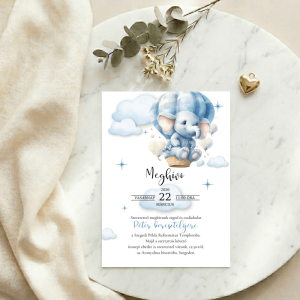 Elefántos fiús meghívó fehér márvány felületen, arany szív alakú medállal és eukaliptusz ággal.